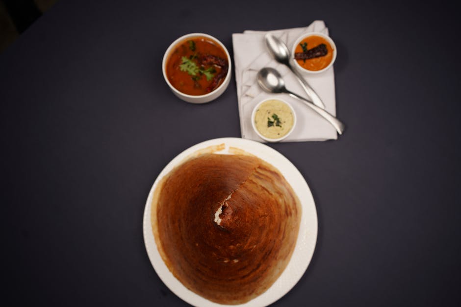 Top view of a traditional South Indian dosa meal with chutneys and sambar.